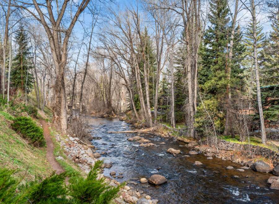 Experience serene living with this stunning property featuring a picturesque river flowing through lush greenery and mature trees.