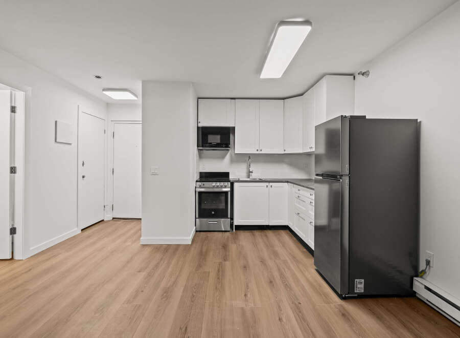This modern kitchen boasts sleek white cabinetry and stainless steel appliances, creating a bright and inviting space.