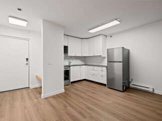 Discover modern living in this stylish apartment featuring a well-equipped kitchen with sleek white cabinetry and stainless steel appliances.