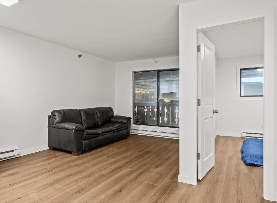 Discover modern living in this stylish apartment featuring a sleek black leather sofa and beautiful hardwood floors.
