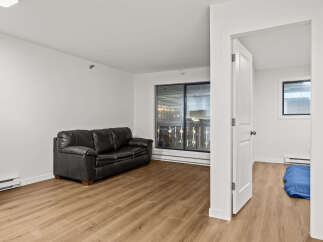 Discover modern living in this stylish apartment featuring a sleek black leather sofa and beautiful hardwood floors.