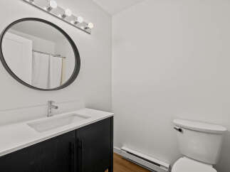 This modern bathroom features a sleek black vanity with a pristine white countertop, offering ample storage and a stylish design.