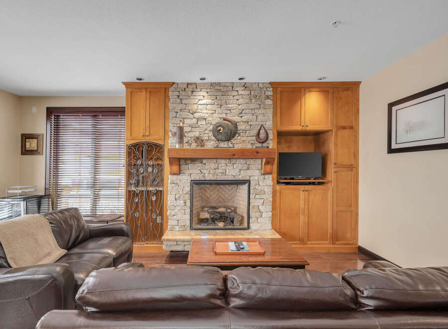 This stunning living room boasts a cozy fireplace with a stone facade, creating a warm and inviting atmosphere.