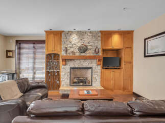 This stunning living room boasts a cozy fireplace with a stone facade, creating a warm and inviting atmosphere.
