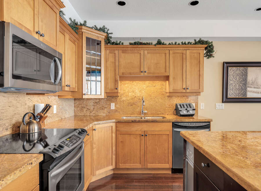This stunning kitchen boasts beautiful wooden cabinetry and granite countertops, creating a warm and inviting atmosphere.