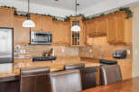 This stunning kitchen boasts beautiful wooden cabinetry, a sleek stainless steel microwave, and a modern stovetop.