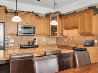 This stunning kitchen boasts beautiful wooden cabinetry, a sleek stainless steel microwave, and a modern stovetop.
