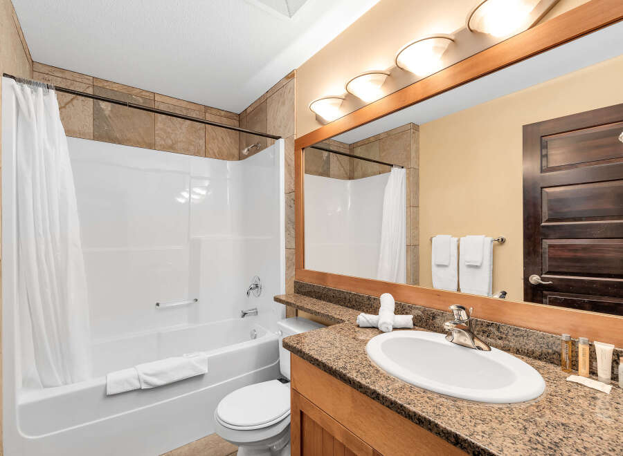 Step into this inviting bathroom, featuring a pristine white bathtub and a stylish vanity with a granite countertop.