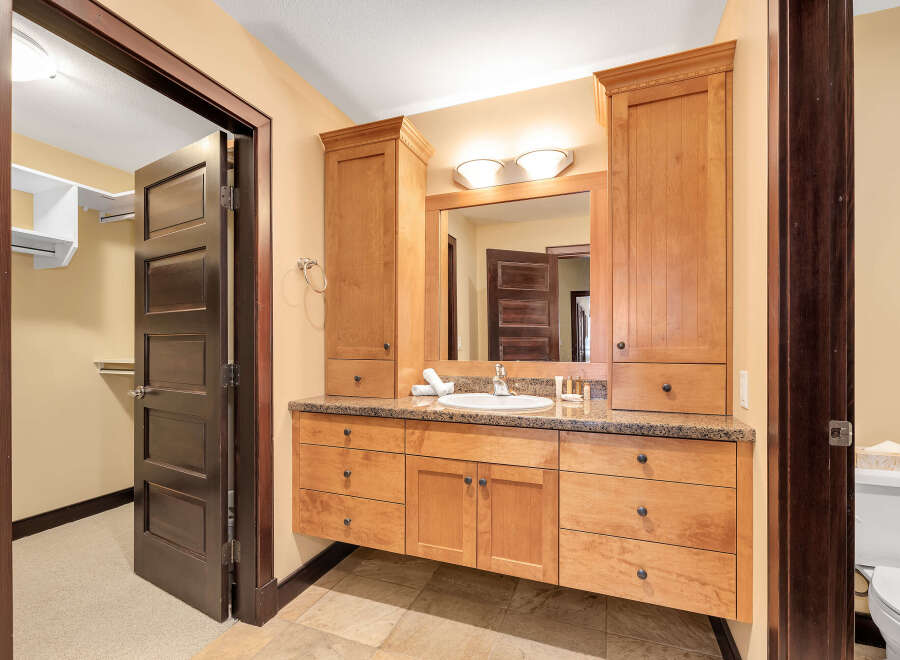 This stunning bathroom boasts custom cabinetry and a granite countertop, offering both style and functionality.