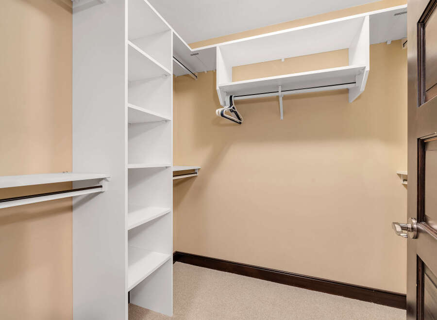 Step into this spacious walk-in closet, offering ample storage with its custom shelving and hanging rods.