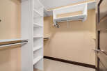 Step into this spacious walk-in closet, offering ample storage with its custom shelving and hanging rods.