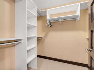 Step into this spacious walk-in closet, offering ample storage with its custom shelving and hanging rods.