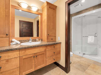 This stunning bathroom boasts a beautiful wooden vanity with ample storage, complemented by a granite countertop.