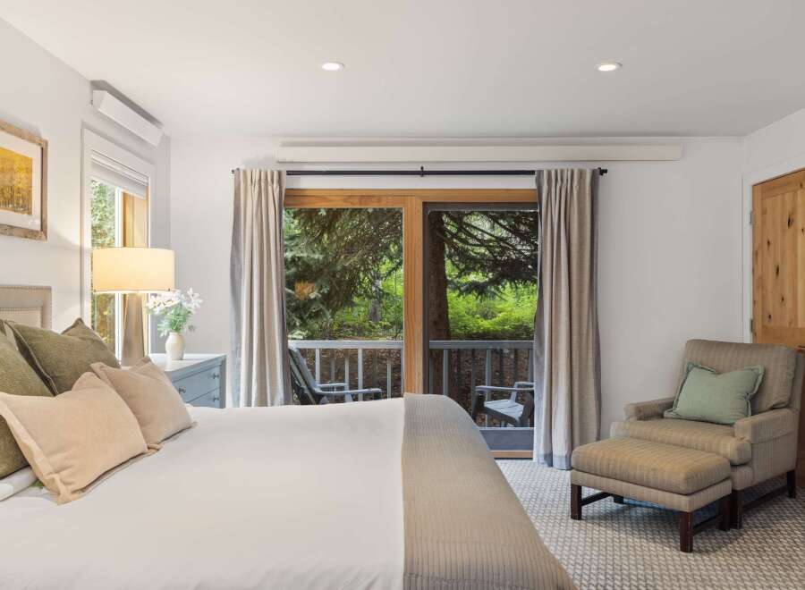 Step into a serene bedroom retreat, where natural light floods through the expansive glass doors leading to a private balcony.
