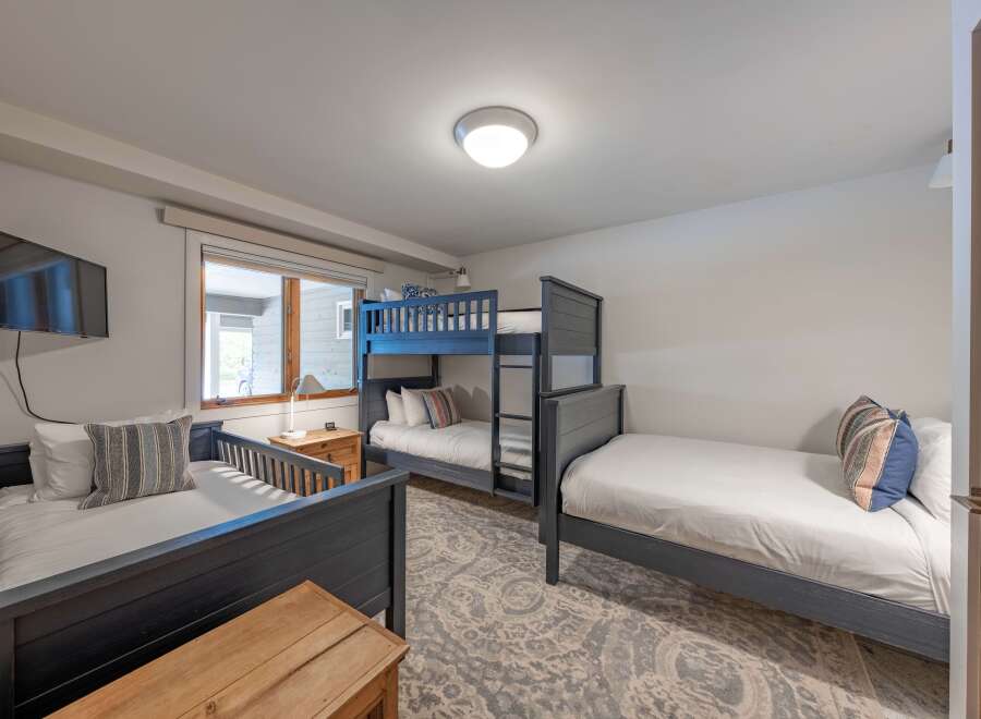 This cozy bedroom features a bunk bed and two twin beds, perfect for accommodating a family or group of friends.