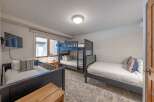 This cozy bedroom features a bunk bed and two twin beds, perfect for accommodating a family or group of friends.