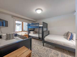 This cozy bedroom features a bunk bed and two twin beds, perfect for accommodating a family or group of friends.