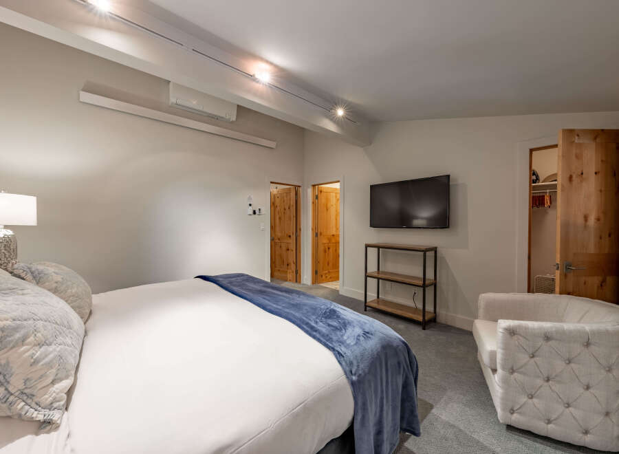 Step into luxury with this stunning bedroom featuring a plush king-sized bed and a cozy armchair, perfect for relaxation.