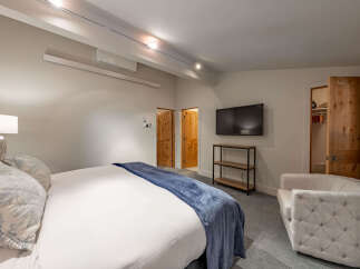 Step into luxury with this stunning bedroom featuring a plush king-sized bed and a cozy armchair, perfect for relaxation.