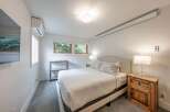 This inviting bedroom offers a serene retreat with its neutral color palette and ample natural light.