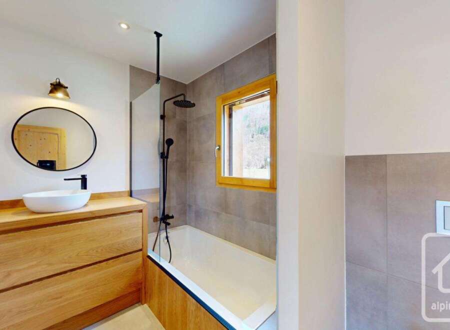 This modern bathroom features a sleek design with a wooden vanity and a round mirror.