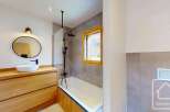 This modern bathroom features a sleek design with a wooden vanity and a round mirror.