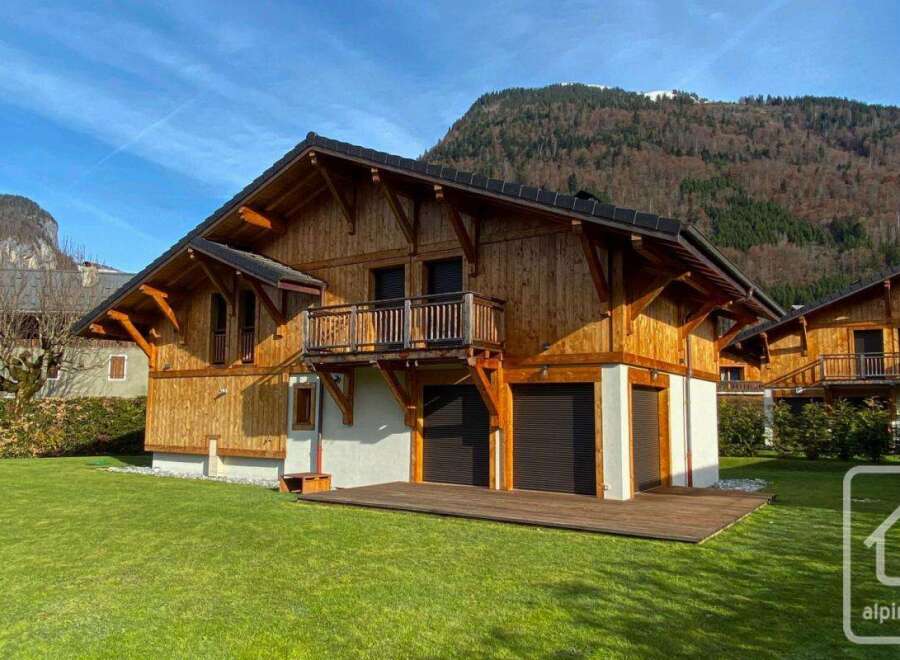 Discover your dream chalet in the heart of the Alps! This stunning property boasts a beautiful wooden facade, a spacious balcony, and a lush green lawn.