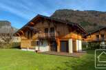 Discover your dream chalet in the heart of the Alps! This stunning property boasts a beautiful wooden facade, a spacious balcony, and a lush green lawn.