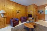 Step into this inviting living space, featuring warm wooden paneling and cozy seating.