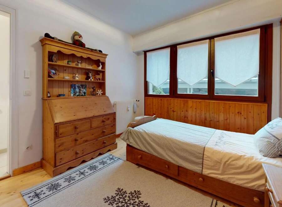 Discover the charm of this cozy bedroom, featuring a warm wooden interior and a comfortable bed.