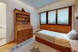 Discover the charm of this cozy bedroom, featuring a warm wooden interior and a comfortable bed.