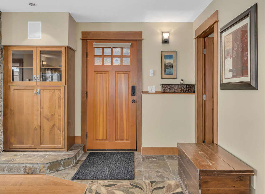 Step into this inviting entryway, showcasing a stunning wooden door and elegant stone flooring.