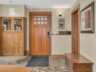 Step into this inviting entryway, showcasing a stunning wooden door and elegant stone flooring.