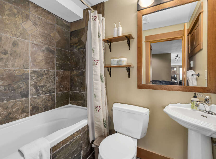 This stunning bathroom features a luxurious stone tile shower surround and a pristine white bathtub, creating a spa-like atmosphere.
