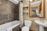 This stunning bathroom features a luxurious stone tile shower surround and a pristine white bathtub, creating a spa-like atmosphere.