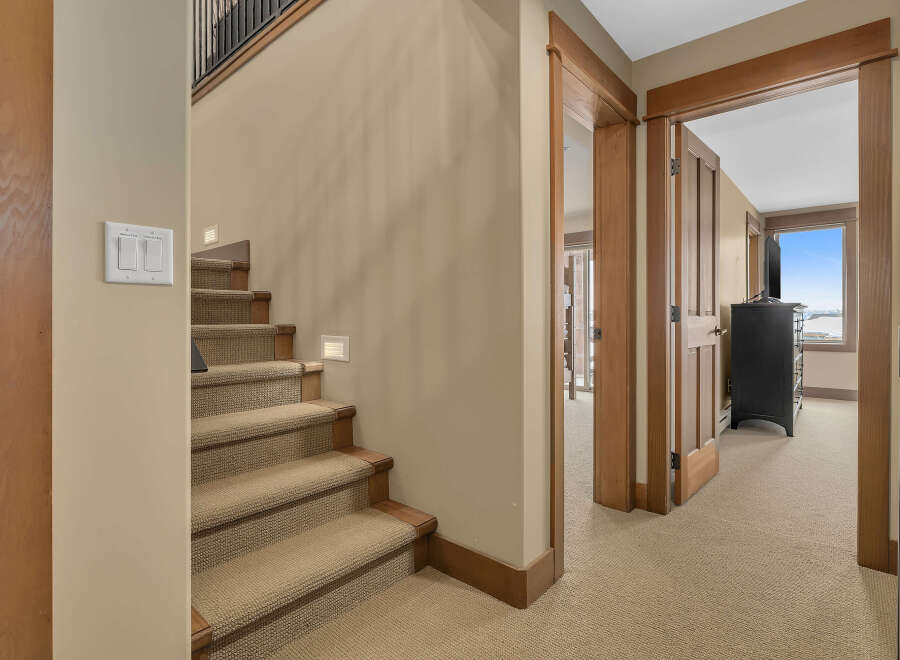 This inviting interior showcases a well-designed staircase with carpeted steps and wooden accents, leading to the upper level.