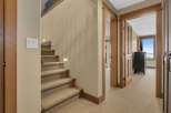 This inviting interior showcases a well-designed staircase with carpeted steps and wooden accents, leading to the upper level.