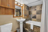 This bathroom features a stylish combination of natural stone tiles and warm wood cabinetry.
