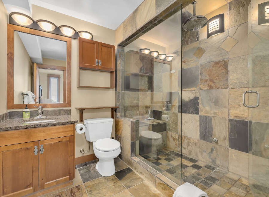 Step into luxury with this stunning bathroom featuring a spacious walk-in shower with a glass door and elegant stone tile.
