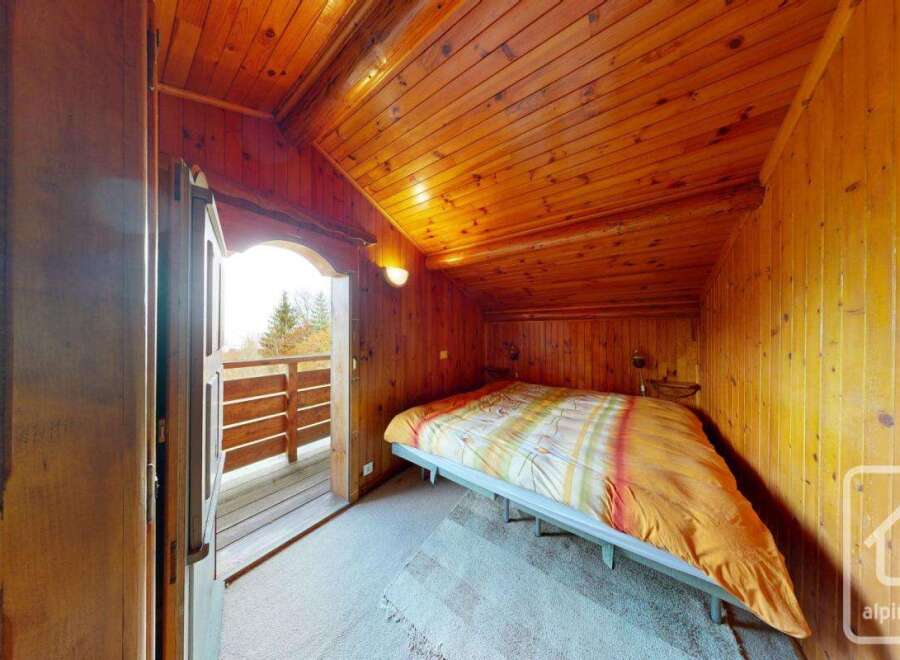 Discover the charm of this cozy bedroom, featuring warm wooden paneling and a unique sloped ceiling.