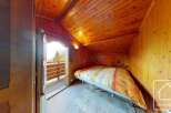 Discover the charm of this cozy bedroom, featuring warm wooden paneling and a unique sloped ceiling.