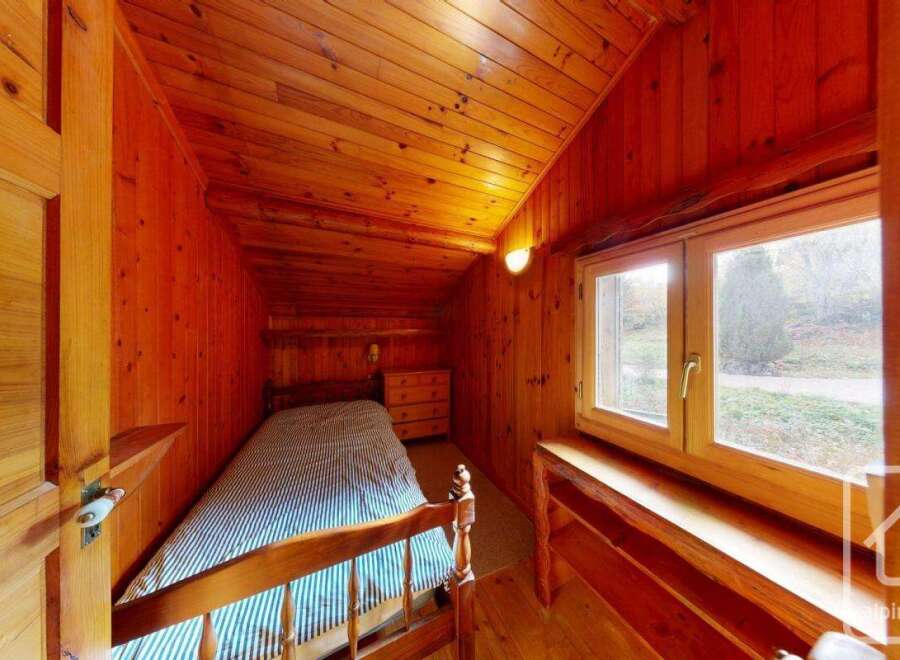 This cozy bedroom features warm wooden paneling throughout, creating a rustic and inviting atmosphere.