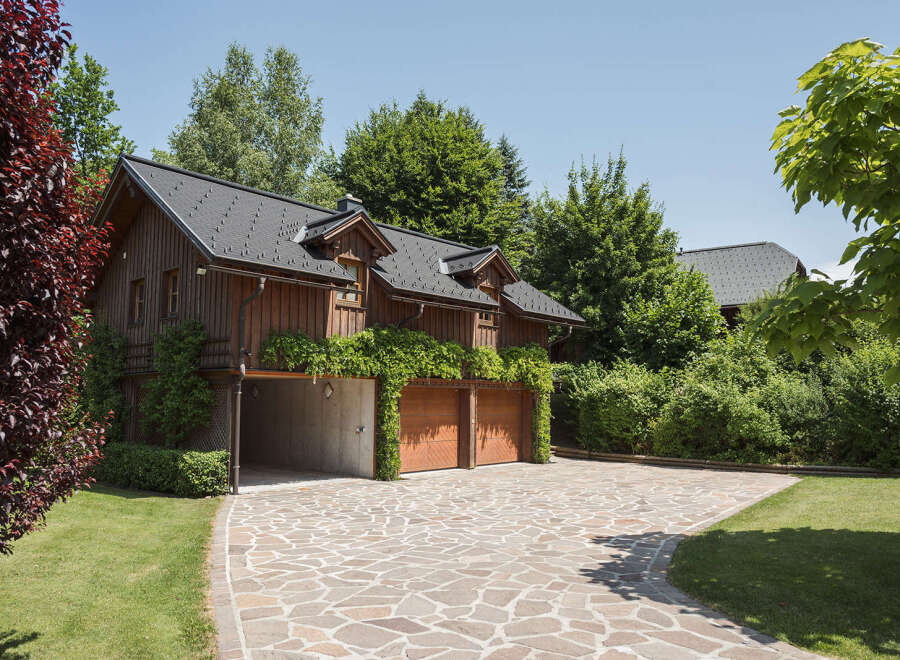 This stunning property boasts a charming wooden exterior and a beautifully designed driveway.