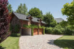 This stunning property boasts a charming wooden exterior and a beautifully designed driveway.