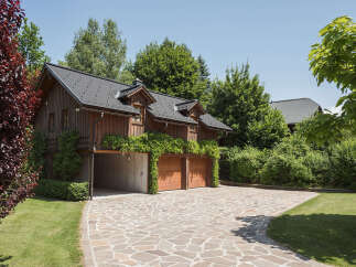 This stunning property boasts a charming wooden exterior and a beautifully designed driveway.