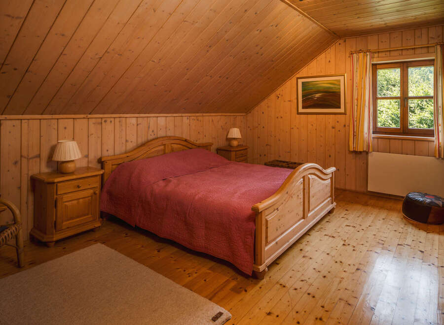 This cozy bedroom features a warm, inviting atmosphere with its wooden walls and flooring.