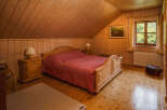 This cozy bedroom features a warm, inviting atmosphere with its wooden walls and flooring.