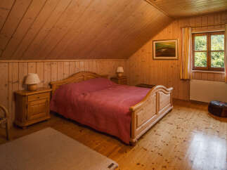 This cozy bedroom features a warm, inviting atmosphere with its wooden walls and flooring.
