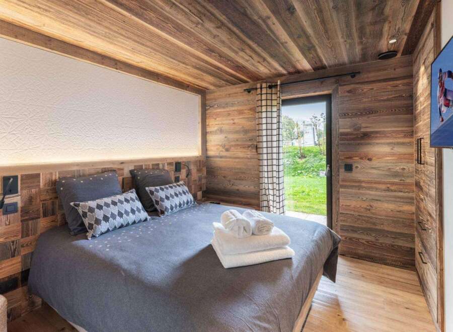 Experience rustic charm in this cozy bedroom, featuring stunning wood paneling and a warm, inviting atmosphere.
