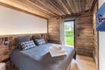 Experience rustic charm in this cozy bedroom, featuring stunning wood paneling and a warm, inviting atmosphere.